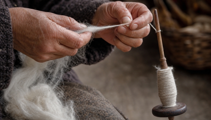 What ancient wooden weighted tool was spun by hand to wind and twist raw wool fibers into yarn?