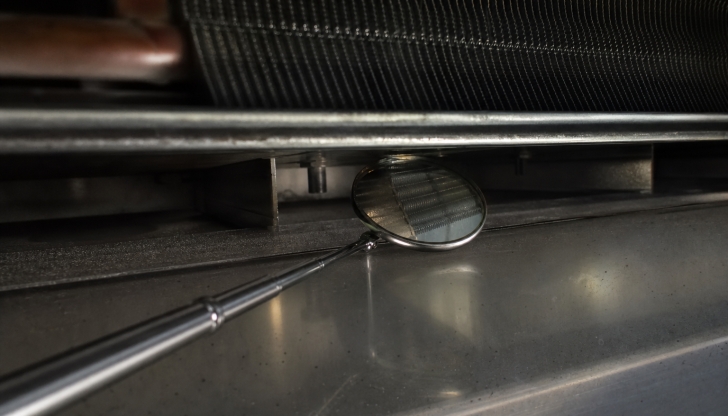 Which simple tool helps you inspect blockages behind dirty coils or look for rust spots?