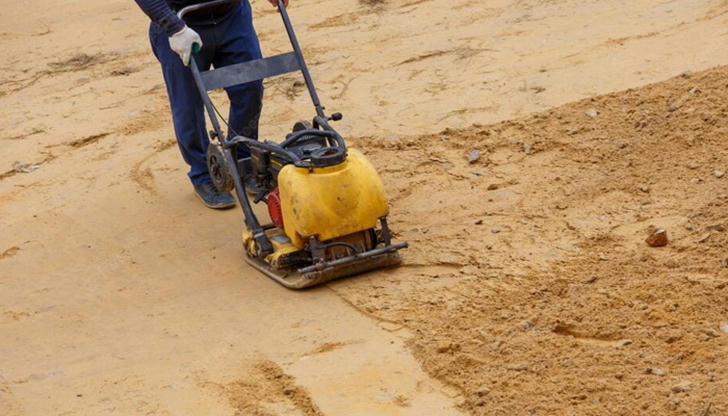 Which equipment compacts soil or gravel before building begins?