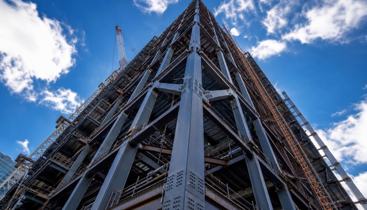 Which tall, iconic machine is anchored to the ground or fixed to the structure to lift concrete, steel, and heavy tools to high-rise building floors?