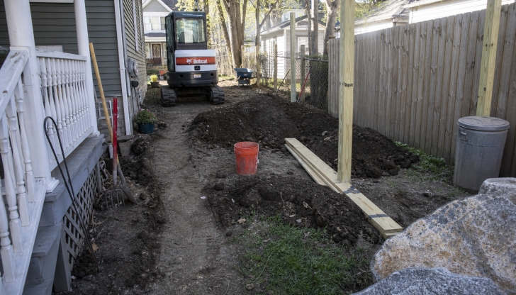 What is the compact, engine-powered machine with lift arms that can fit various attachments (like buckets or augers) and can spin within its own footprint?