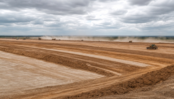 Which large, articulated earthmoving machine loads soil into a central hopper by scraping the ground as it moves, then hauls and dumps it?