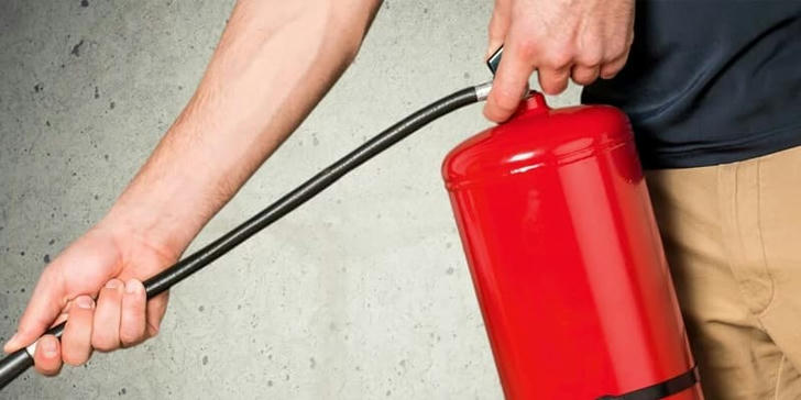 What is the proper first step when using a fire extinguisher?