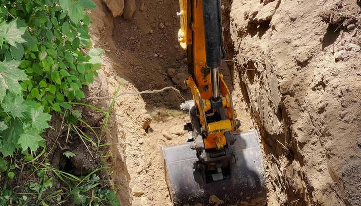 An excavator pulling soil out of the ground is doing what?