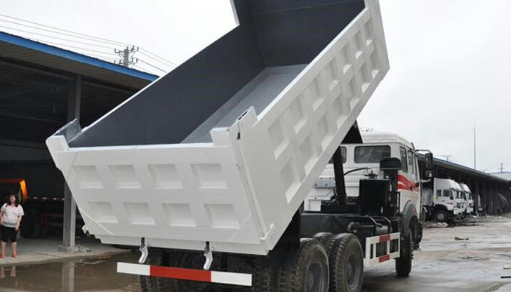 What feature best distinguishes a dump truck from a flatbed truck?