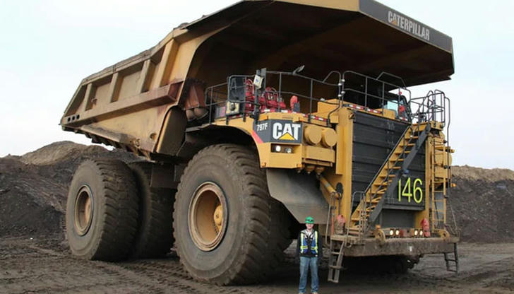Why should people avoid standing close behind a dump truck?
