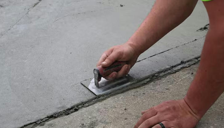 Which tool would you choose to create a clean edge along a concrete sidewalk, and not for smoothing the center surface?