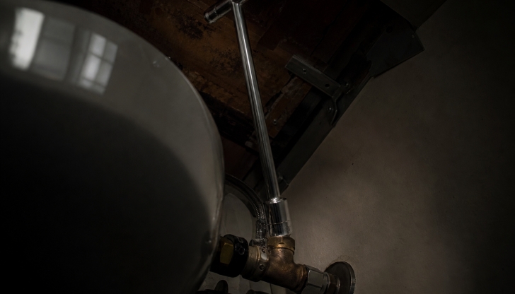 Which specialty wrench features a long steel shaft and a pivoting jaw at the tip to reach the nuts deep behind sink bowls?