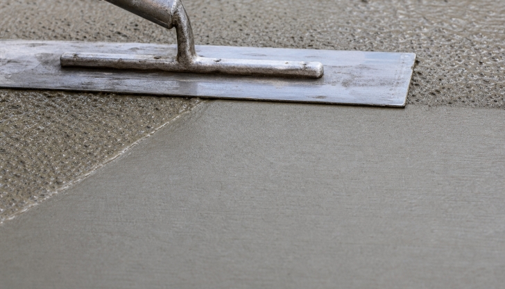 Why do concrete finishers prefer a Magnesium Hand Float over a steel hand trowel during the initial wet stage?