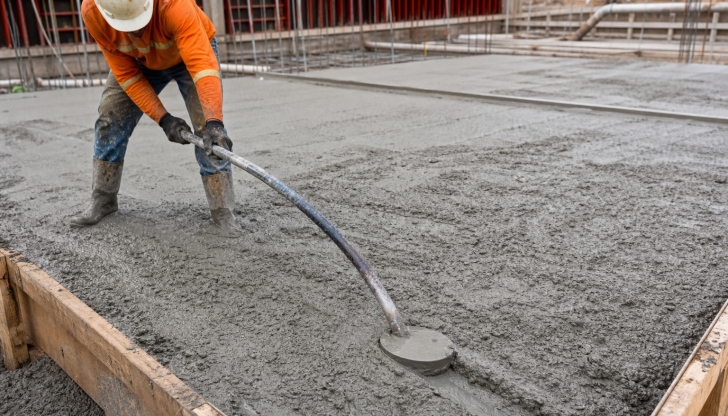 What heavy metal rake with a curved, solid hook-like blade is used to pull and distribute wet concrete when it first drops from the mixer chute?